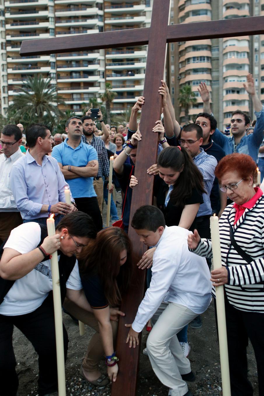 Jóvenes colocan la cruz en la orilla para orar por los fallecidos en el Mediterráneo