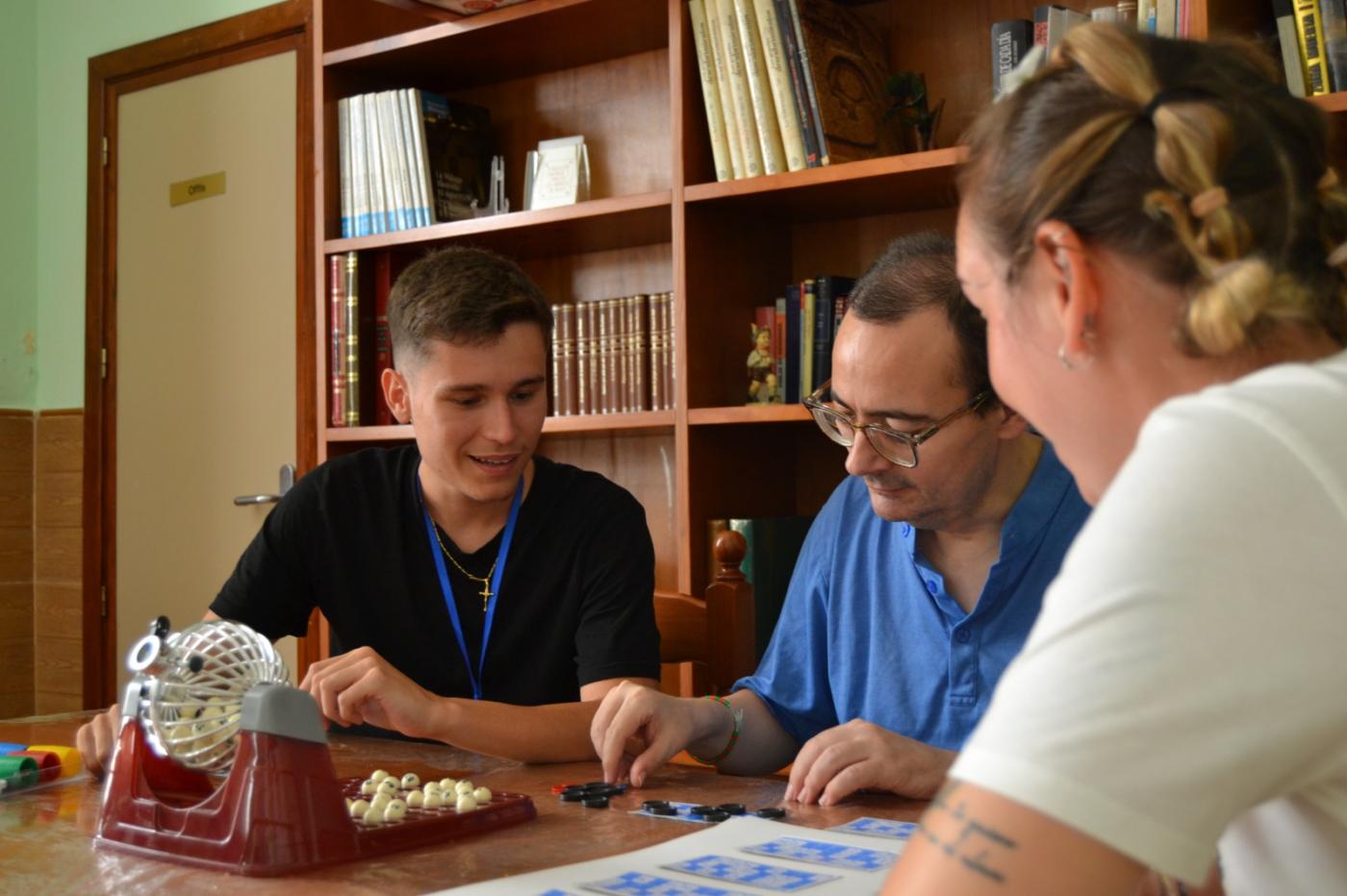 Dos voluntarios juegan con una persona acogida en el Hogar Pozo Dulce